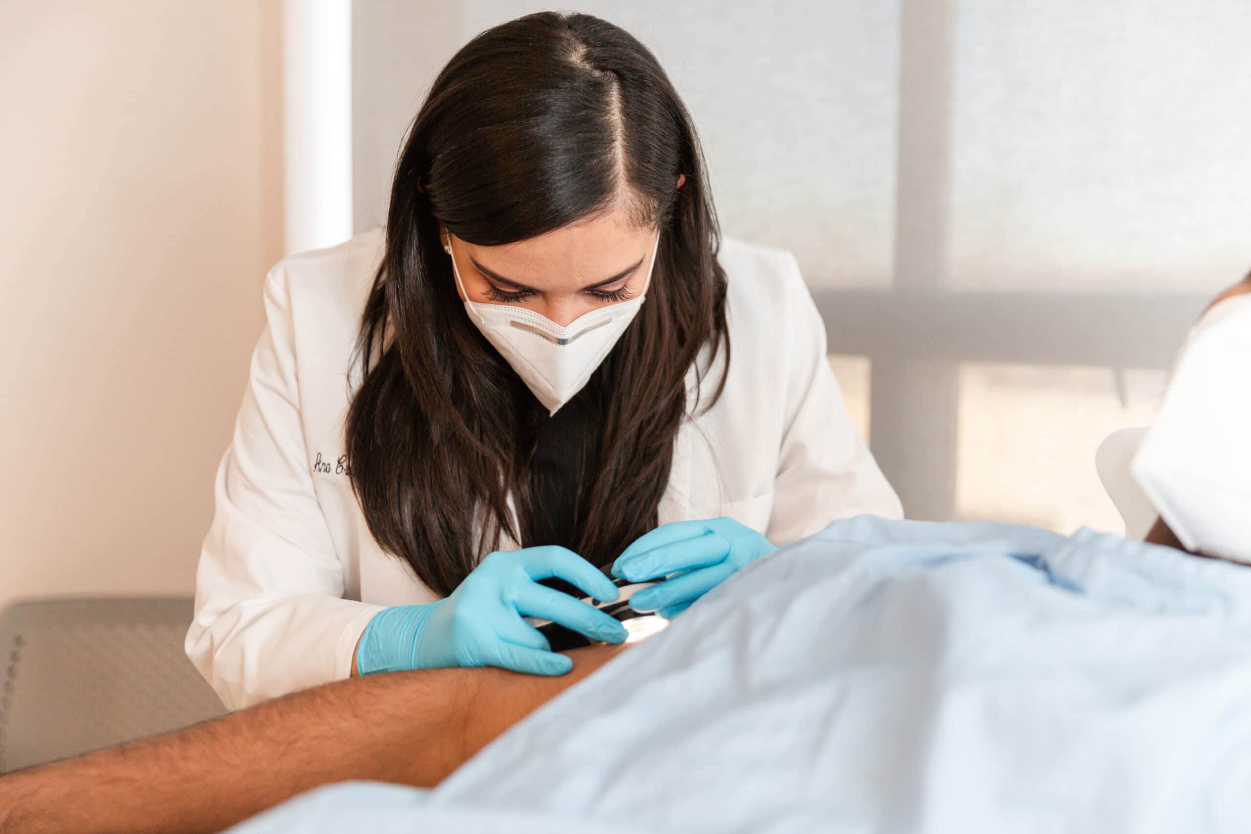 scherl-dermatology-dr-laureano-checking-skin dermatologist reviewing patient's skin to find atypical moles